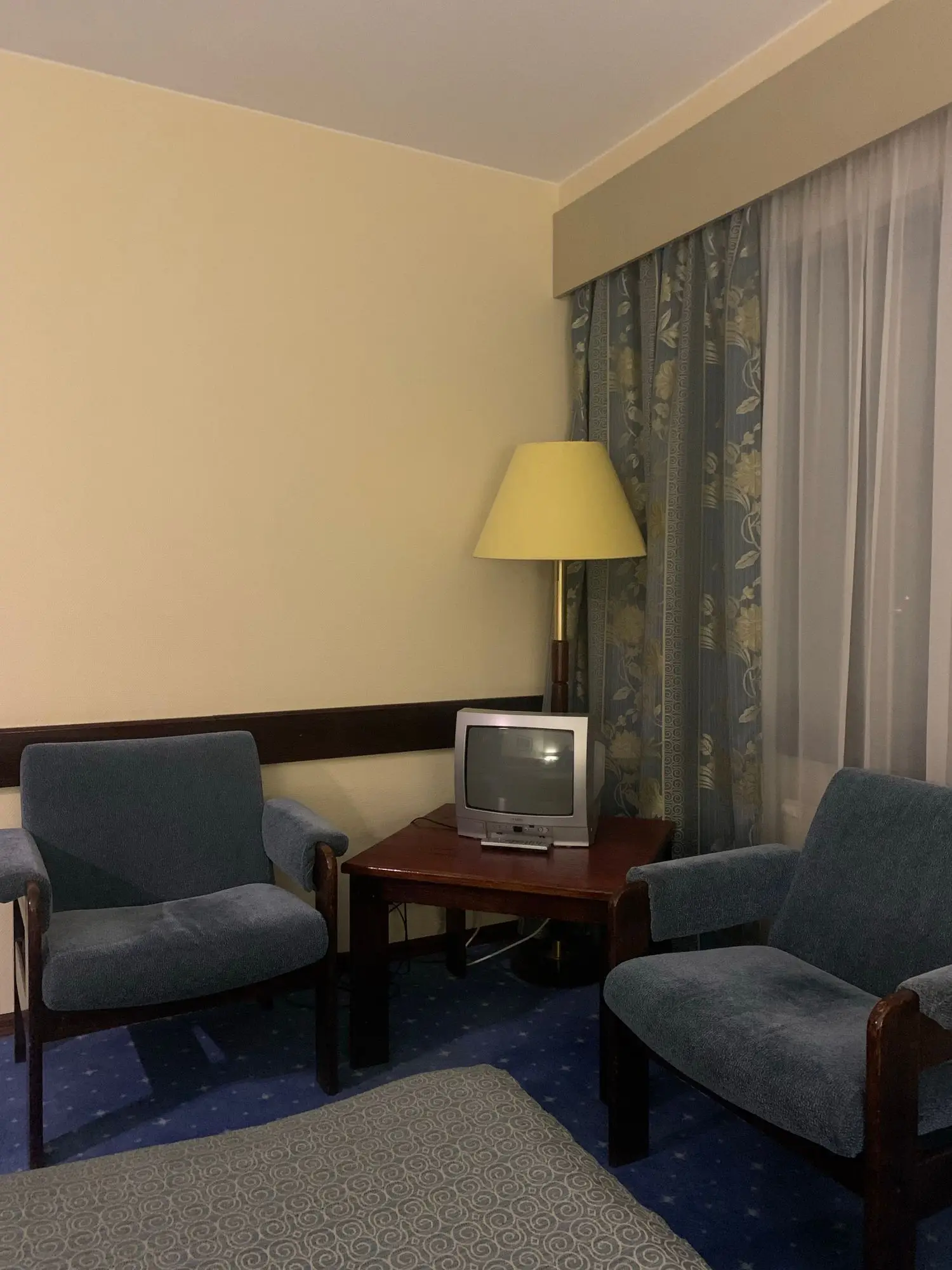 Hotelzimmer mit Sofa, Tisch und klassischer Stehleuchte