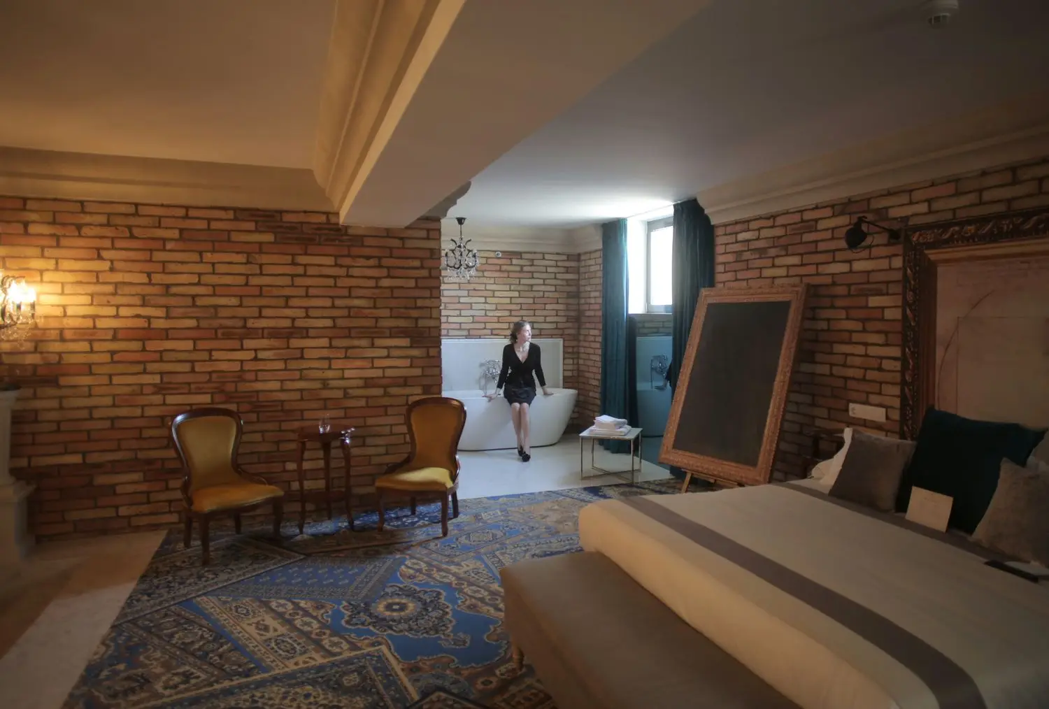 Großzügiges Hotelzimmer mit Backsteinwand und separater Sitzecke